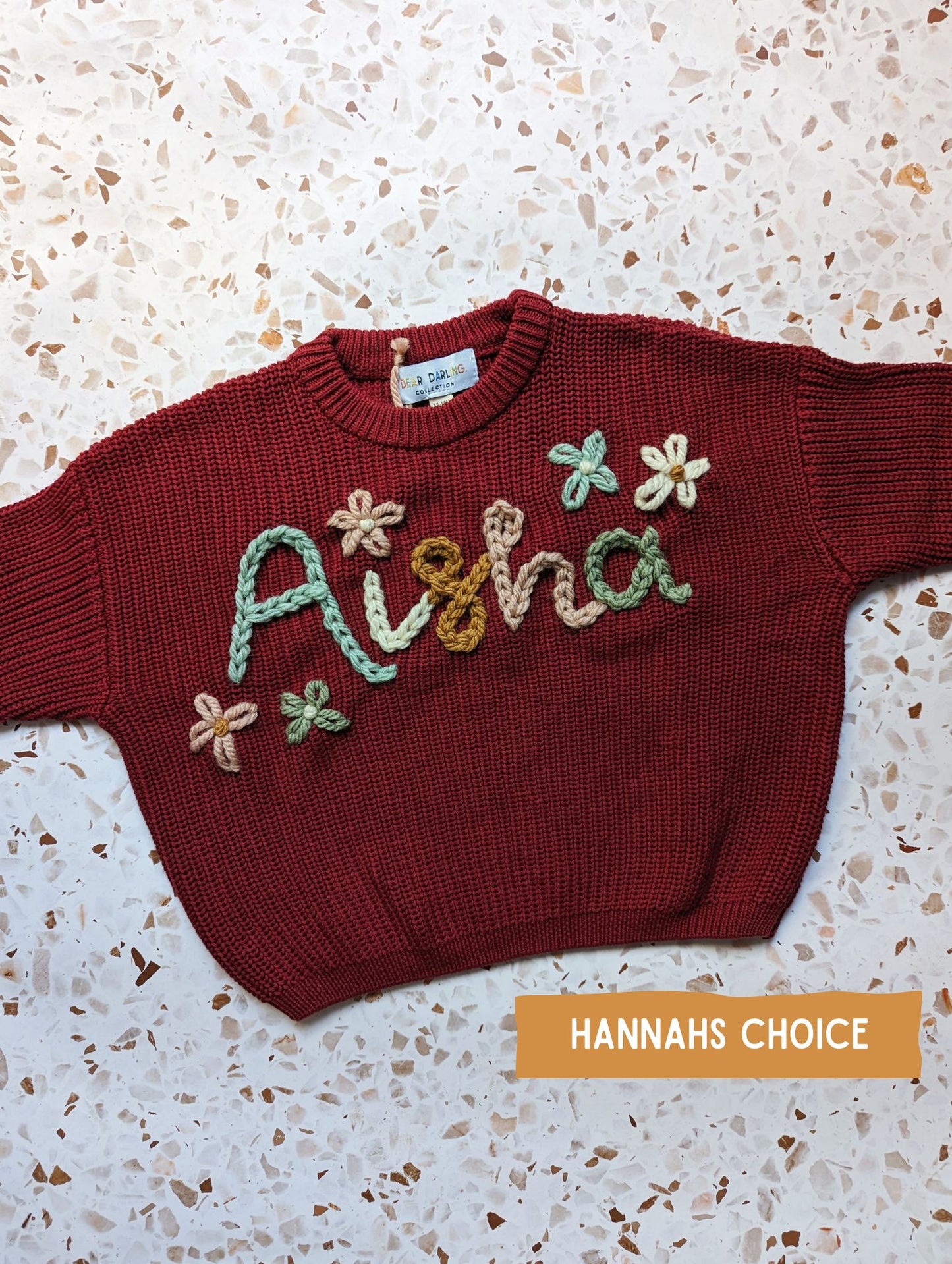 hand embroidered name knit with multicolour yarn spelling childrens name with flowers surrounding