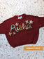 hand embroidered name knit with multicolour yarn spelling childrens name with flowers surrounding